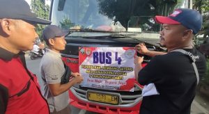 Memasang banner tuntutan jabatan 9 tahun di bus. Tampak pejabat Dinpermades Kabupaten Rembang melepas keberangkatan Kades ke Jakarta, Senin sore (16/01).